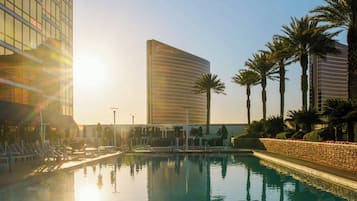 Una piscina con agua cristalina, rodeada de palmeras y edificios modernos.