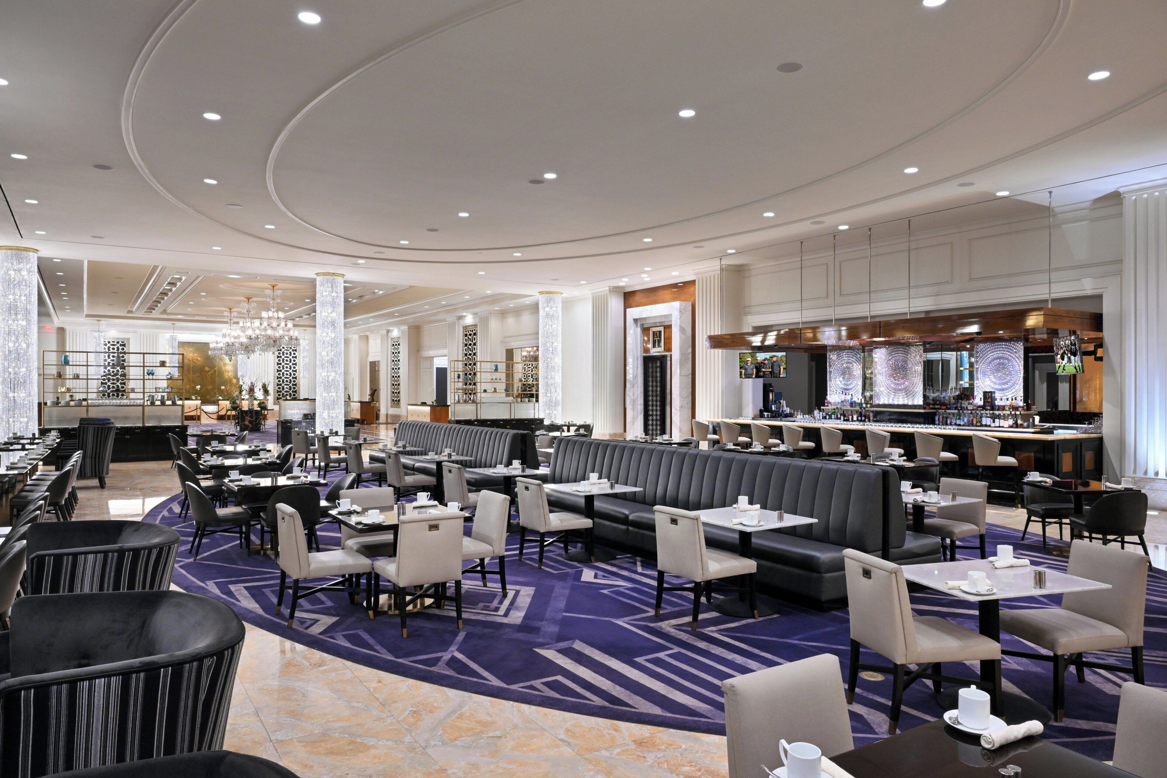 A hotel lobby with a bar area, seating arrangements, and a decorative ceiling.