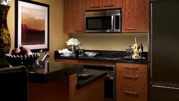 A modern kitchen with wooden cabinets, stainless steel appliances, and a marble countertop.