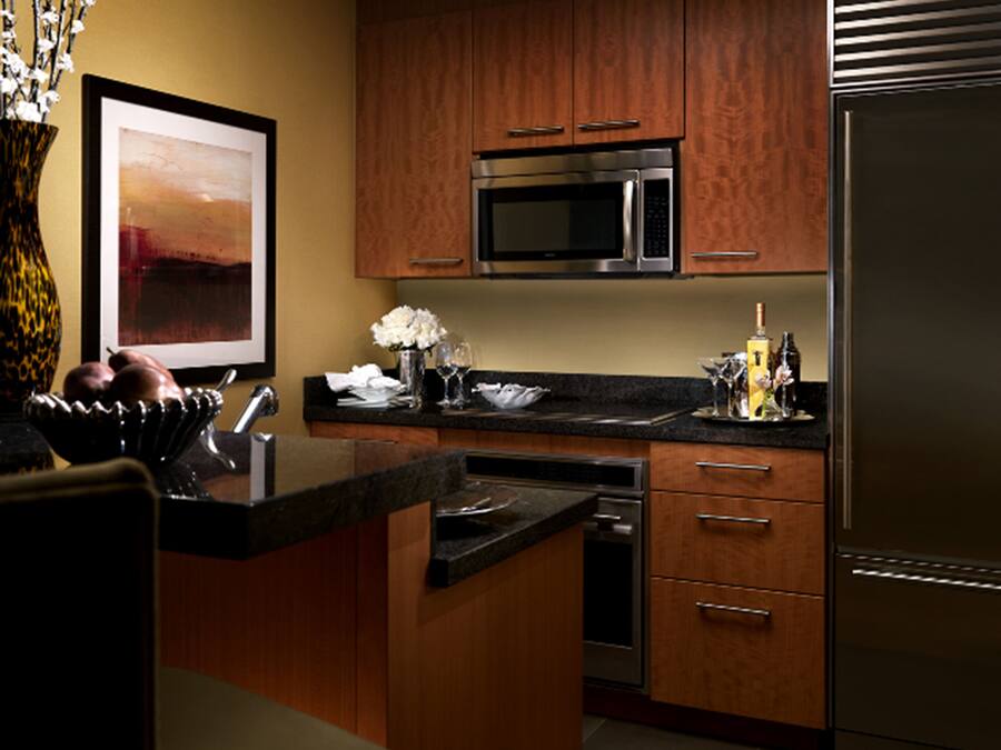 A modern kitchen with wooden cabinets, stainless steel appliances, and a marble countertop.