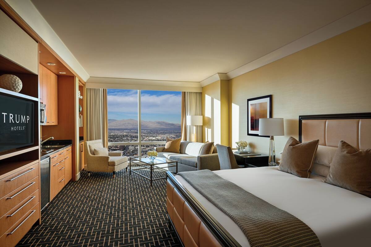 Une chambre d’hôtel avec un grand lit, une télévision, un bureau et une vue sur la ville.