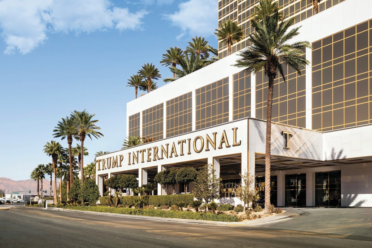 Un hotel Trump International con una facciata moderna, palme e cielo sereno.