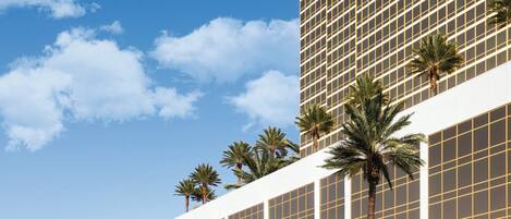 Un hotel Trump International con fachada moderna, palmeras y cielo despejado.