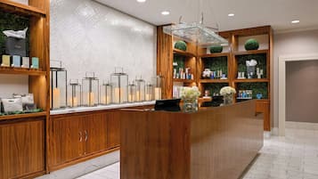 A hotel reception area with wooden cabinets, a marble floor, and a glass display case with candles.