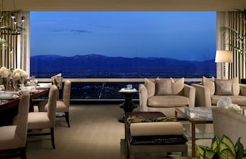A modern living room with a sofa, coffee table, and lamps. A cityscape and mountains are visible through the window. at Trump International Hotel Las Vegas