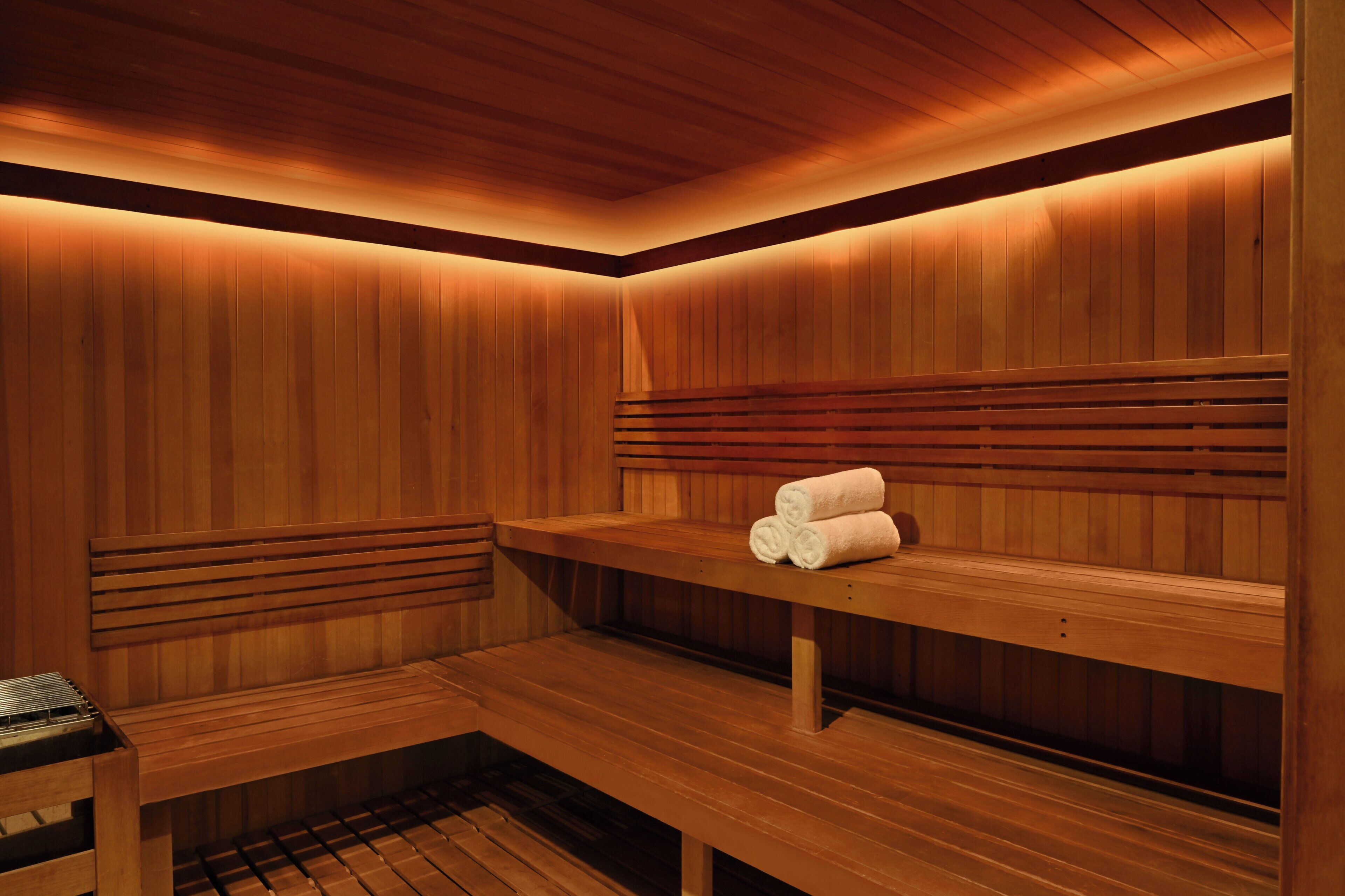 Un sauna avec des bancs en bois et un banc où sont disposées des serviettes.