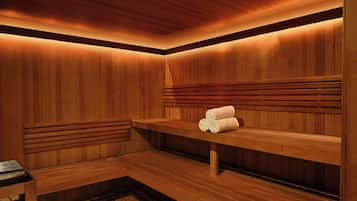 Un sauna avec des bancs en bois et un banc où sont disposées des serviettes.
