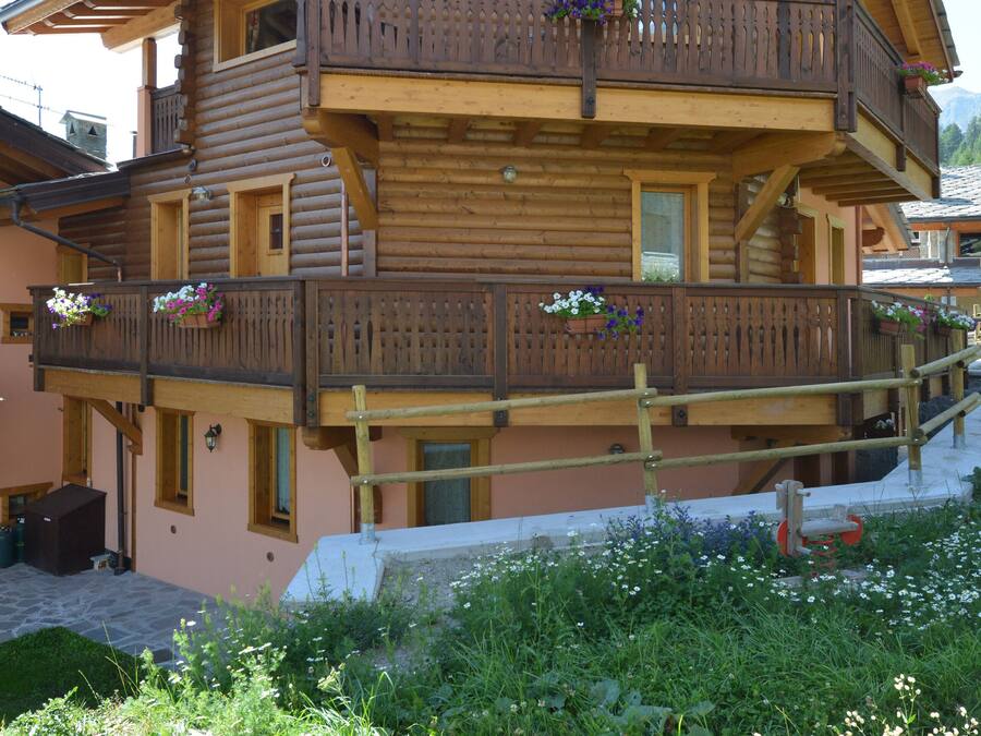 Un chalet de madera de varios pisos con balcones decorados con jardineras florales.