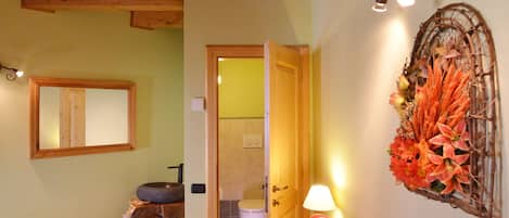A cozy room with a wooden ceiling, a patterned sofa, a mirror, and a decorative wall piece.
