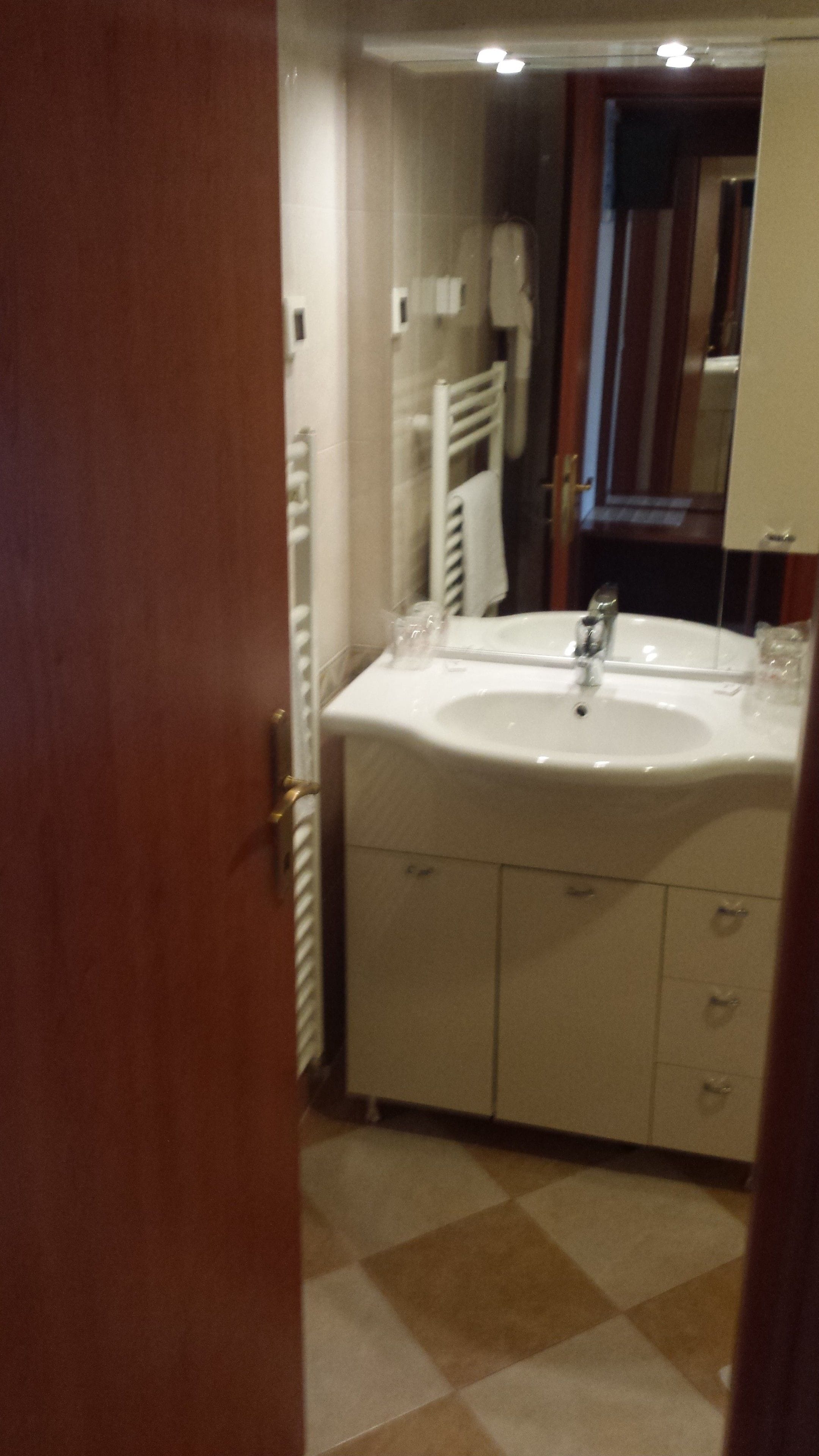 A bathroom with a sink, mirror, and towel rack.