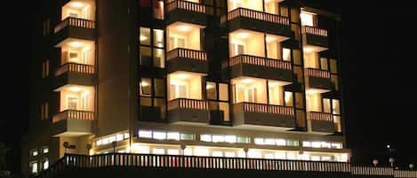 A multi-story hotel with balconies and illuminated windows at night.