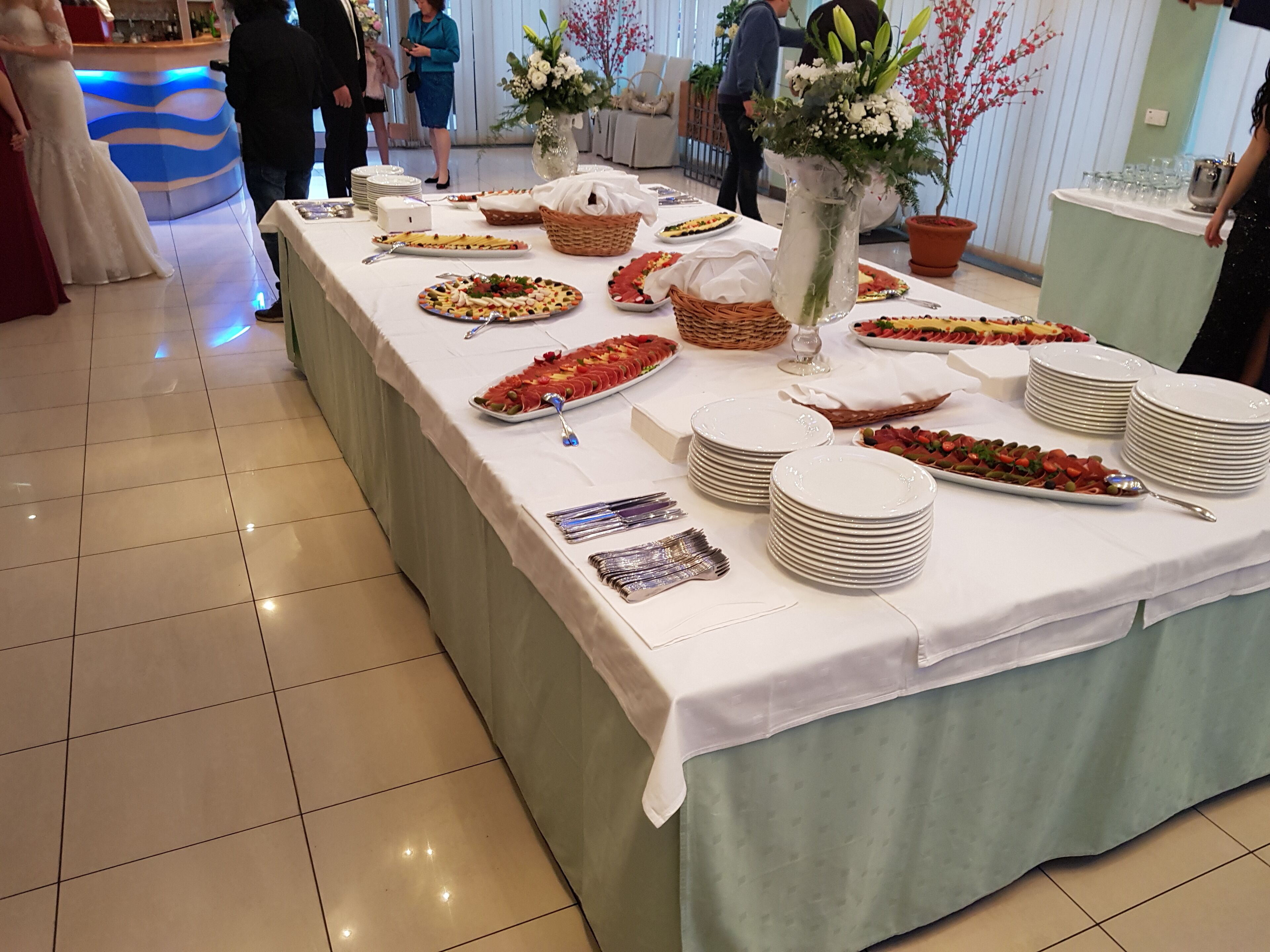 A buffet table with various dishes, plates, and utensils.