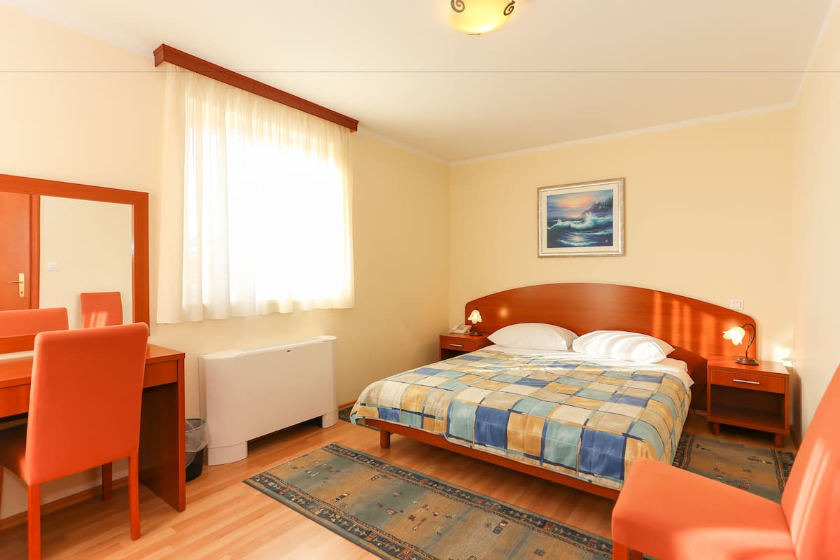A bedroom with a bed, bedside tables, a desk, and a chair.