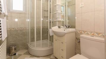 Un baño con ducha de vidrio, lavamanos e inodoro.