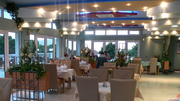 A restaurant with multiple tables, chairs, and a ceiling with lights. - Aparthotel Astoria (Seget)