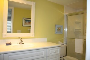 Un baño con tocador blanco, un espejo grande y una cabina de ducha de vidrio.