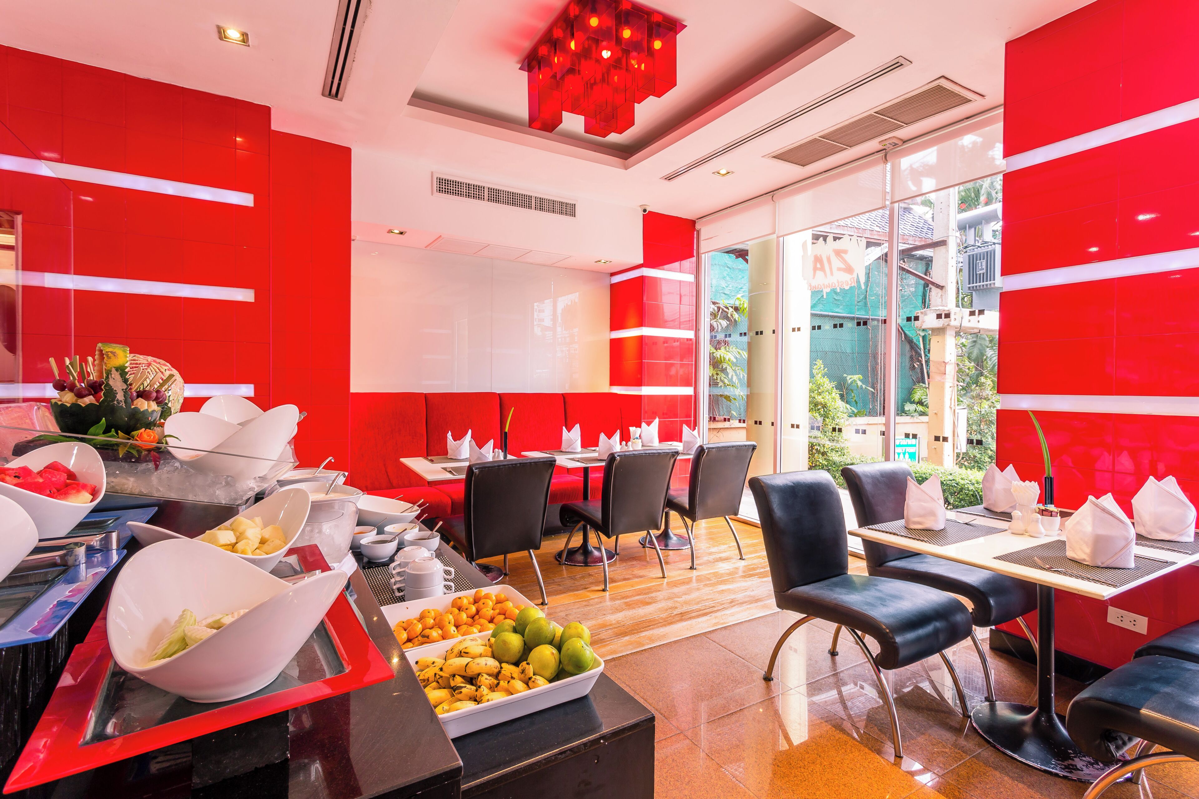 Un restaurante moderno con paredes rojas, un bufé de frutas y verduras, y sillas negras.