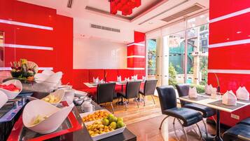 Un restaurante moderno con paredes rojas, un bufé de frutas y verduras, y sillas negras.