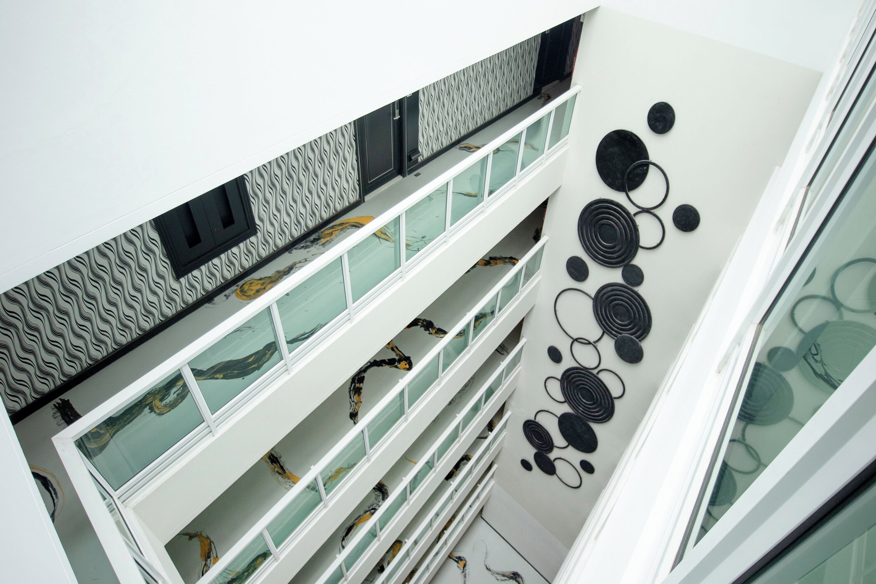 A multi-level interior with glass railings and a patterned wall design.
