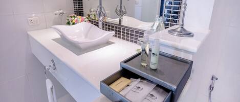 A modern bathroom with a white sink, two faucets, a mirror, and a shower area.
