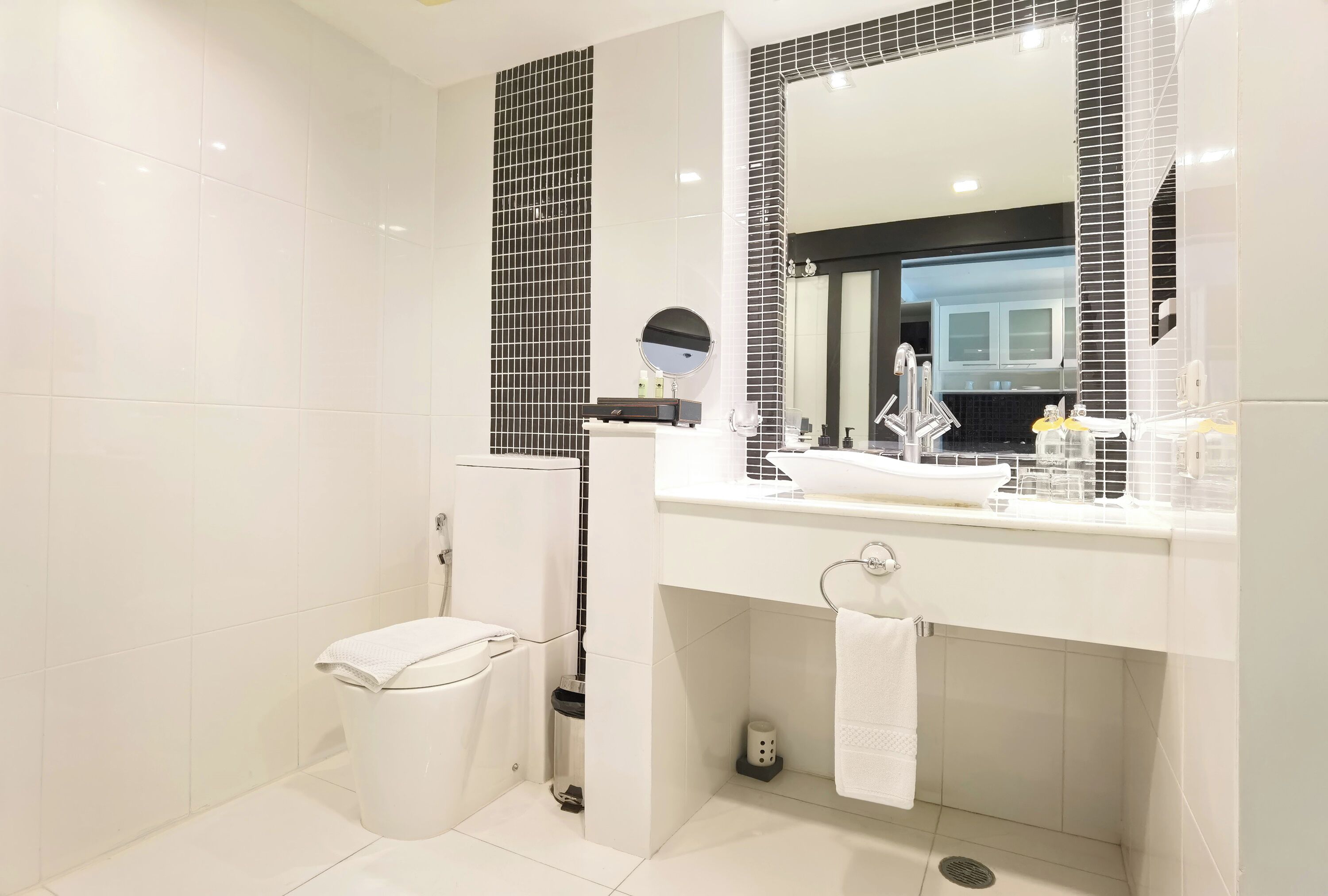 Un baño moderno con un lavamanos blanco, un espejo grande y un inodoro.