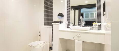 Un baño moderno con un lavamanos blanco, un espejo grande y un inodoro.