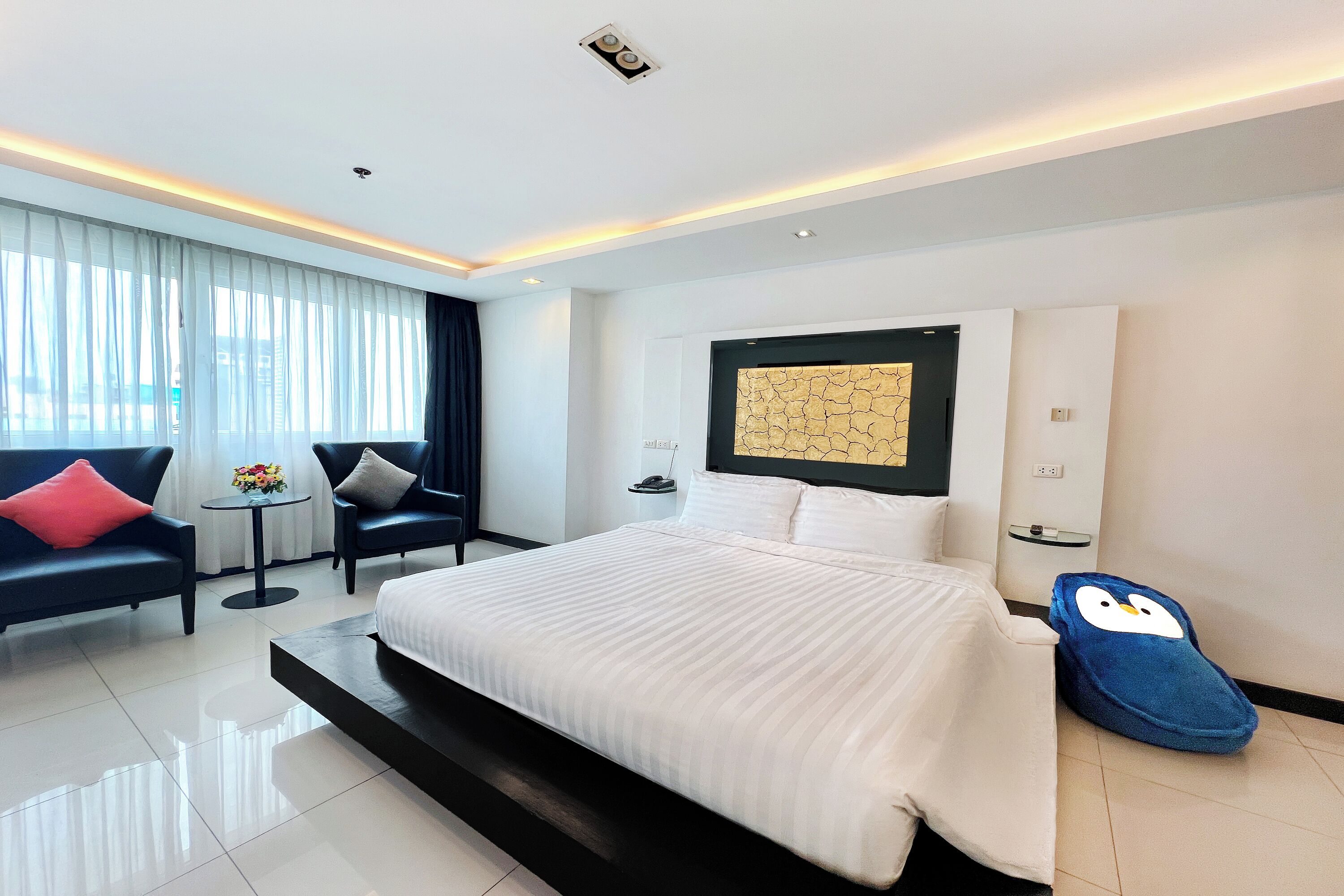 Une chambre d’hôtel moderne, dotée d’un grand lit, d’un bureau, d’une chaise et d’un élément décoratif mural.