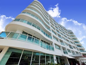A modern hotel with a curved facade, multiple balconies, and large windows. - Nova Suites Pattaya by Compass Hospitality (Pattaya)