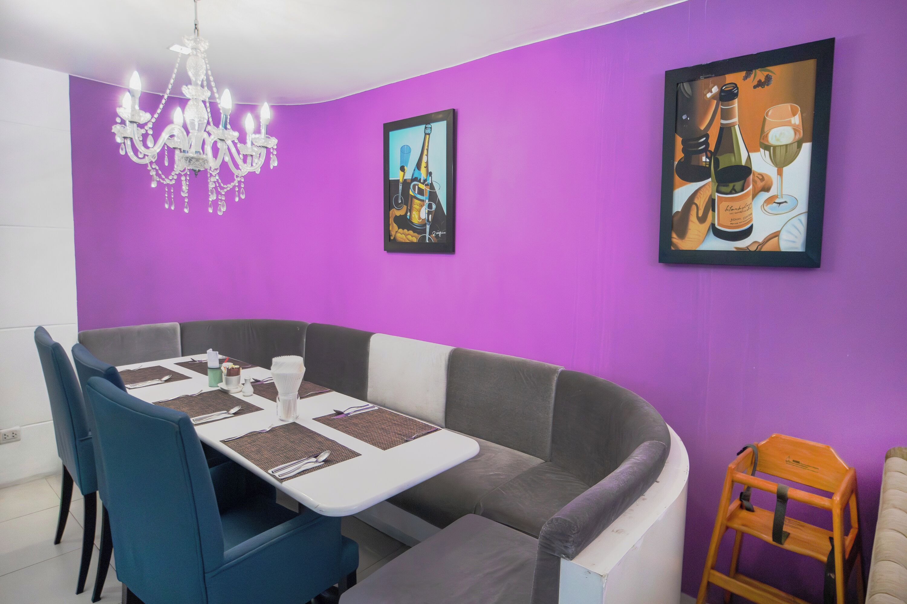 A dining area with a table set for two, a sofa, and a small wooden chair.