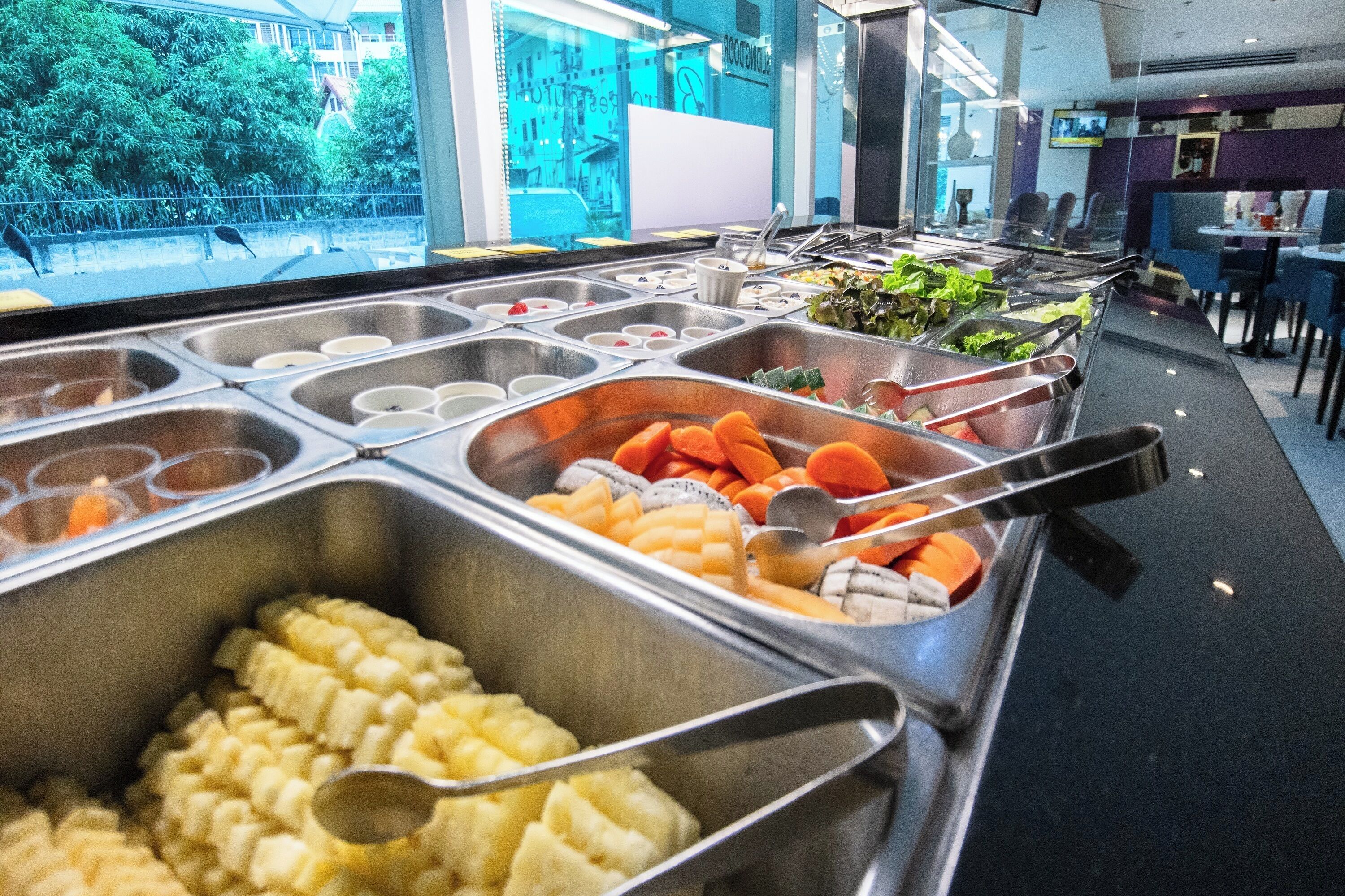 A buffet with various food options including fruits, vegetables, and salads.