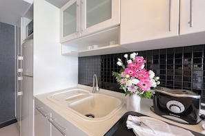 A modern kitchen with a white sink, black backsplash, and a toaster. - Nova Suites Pattaya by Compass Hospitality (Pattaya)