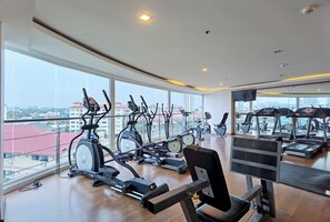 A gym with various exercise equipment, large windows, and a city view. - Nova Suites Pattaya by Compass Hospitality (Pattaya)