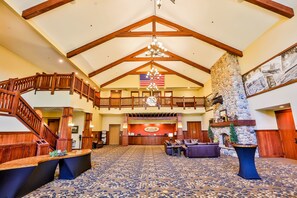A spacious lobby with a high ceiling, wooden staircase, and a reception desk.