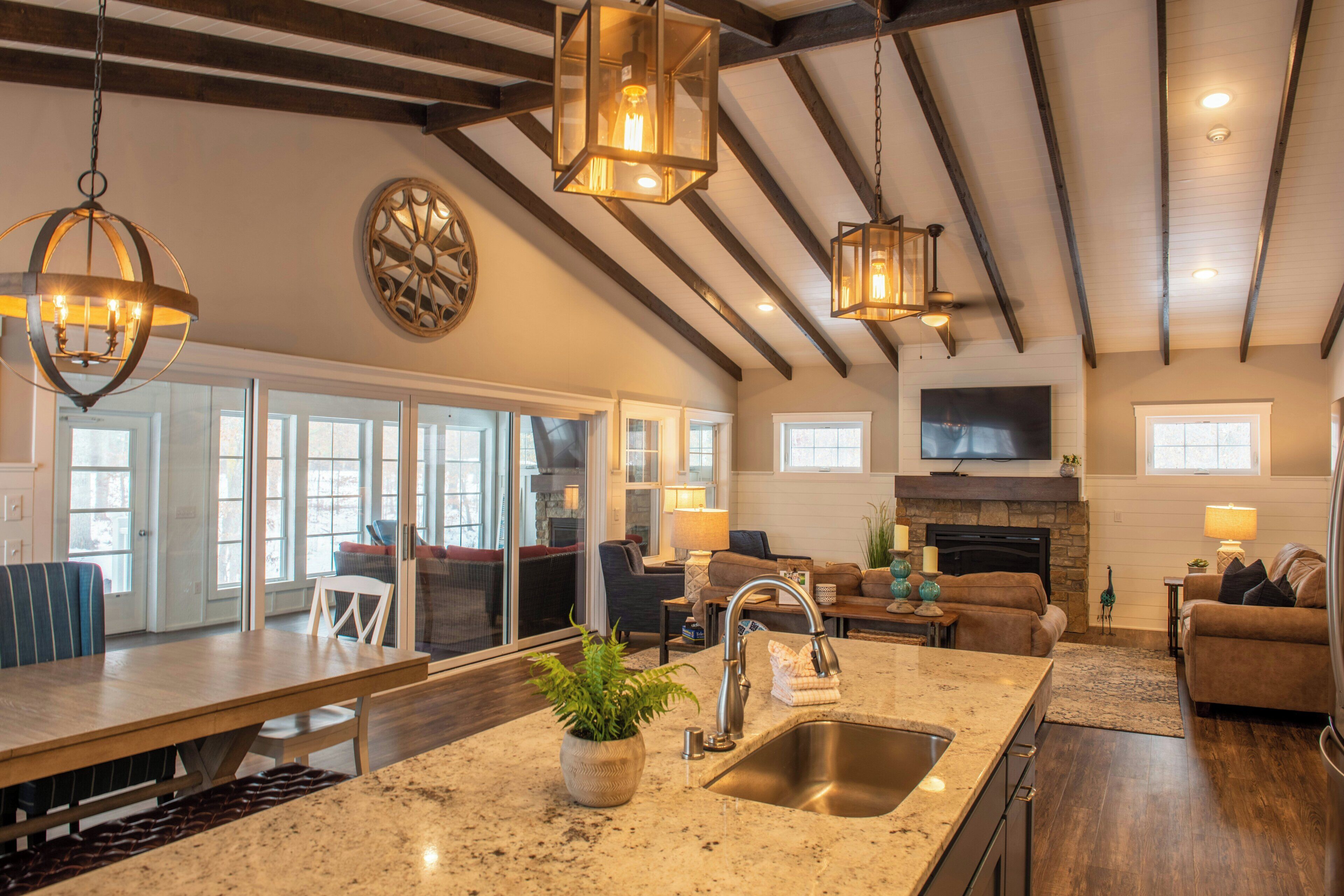 A spacious kitchen with a large island, a dining area with a long table, and a living room with a fireplace.