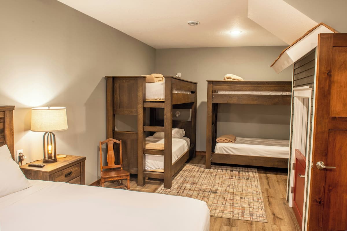 Habitació amb llits superposats, una taula de nit amb una làmpada, una cadira i una porta.