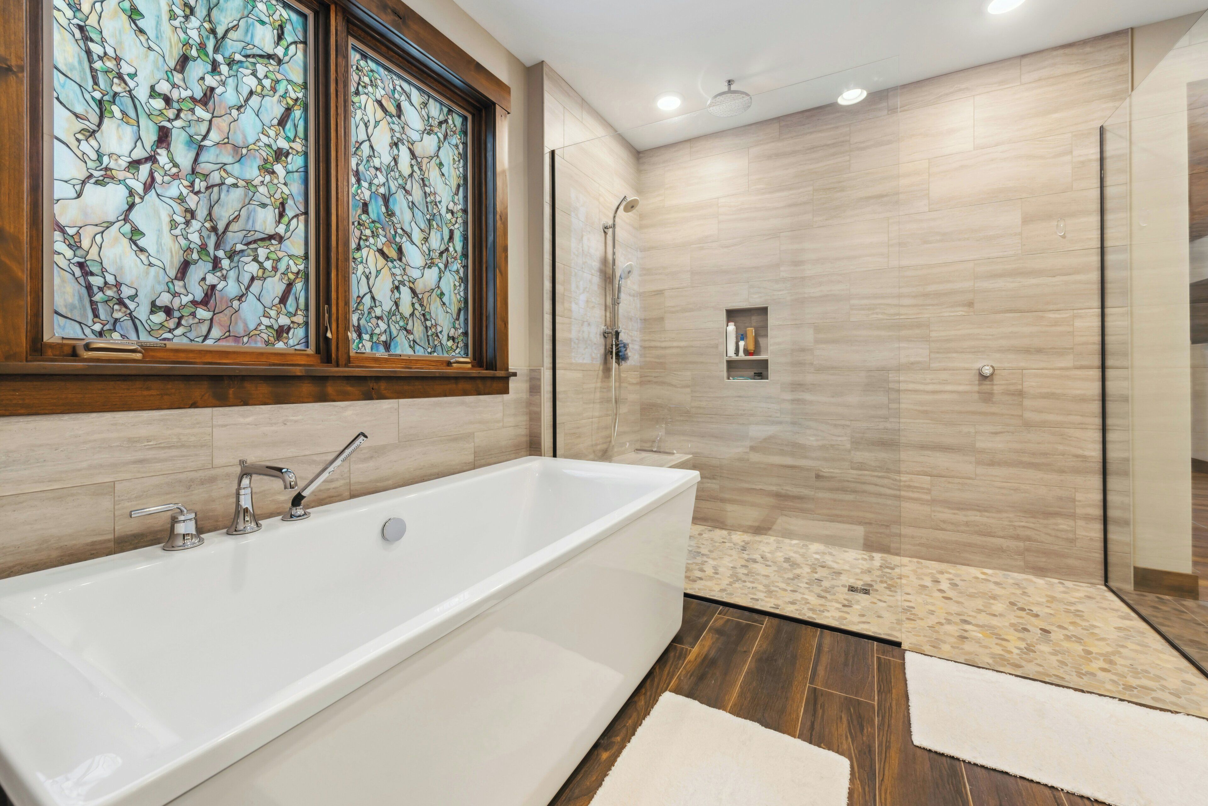 A modern bathroom with a bathtub, shower, and glass doors.