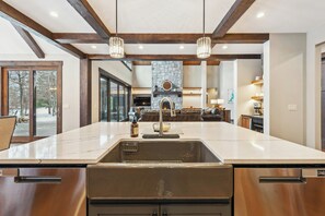 A modern kitchen with a large island, built-in appliances, and a stone fireplace.