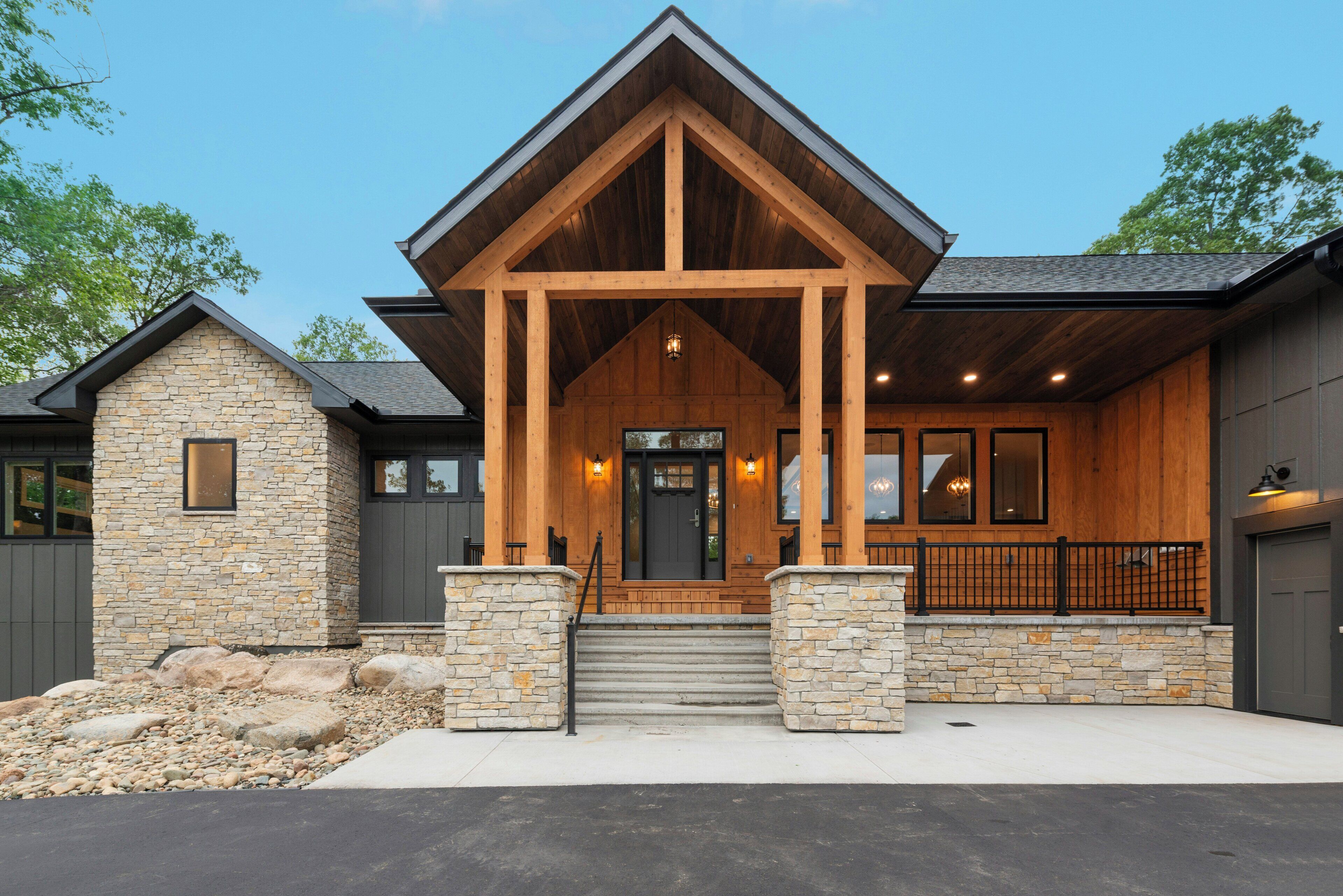 A modern building with a stone facade, wooden entrance, and a covered porch.