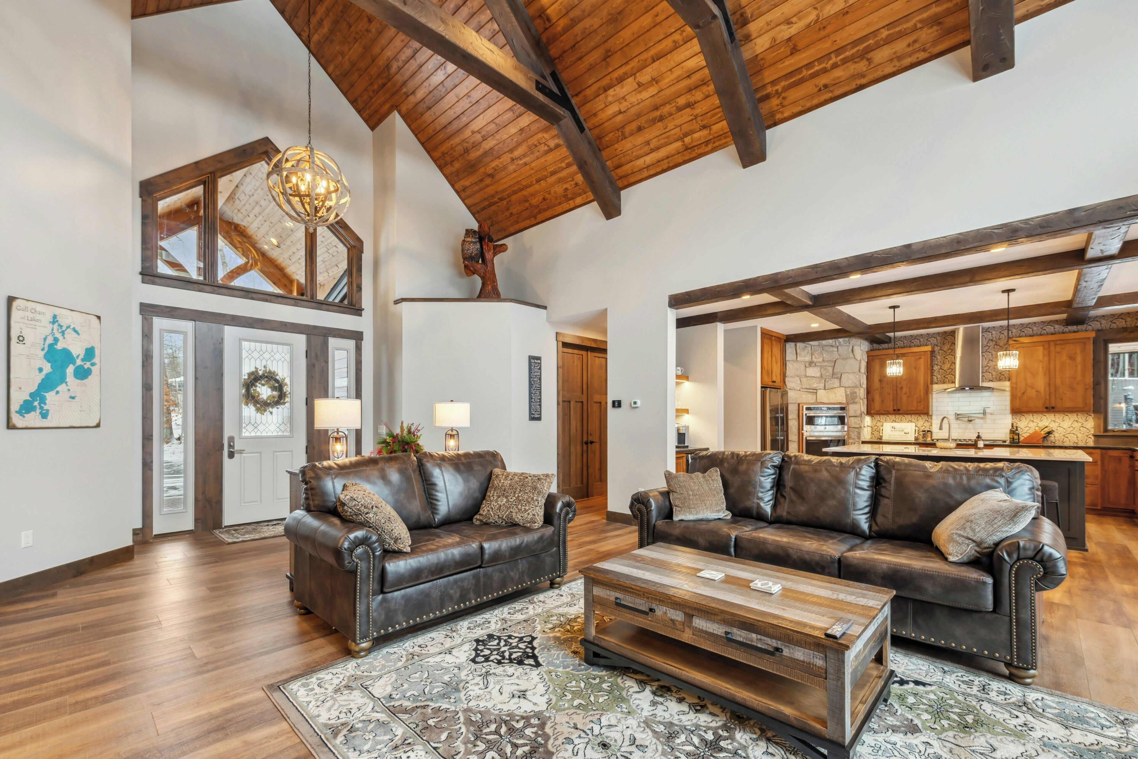 A spacious living room with leather sofas, a wooden coffee table, and a high ceiling with exposed beams.