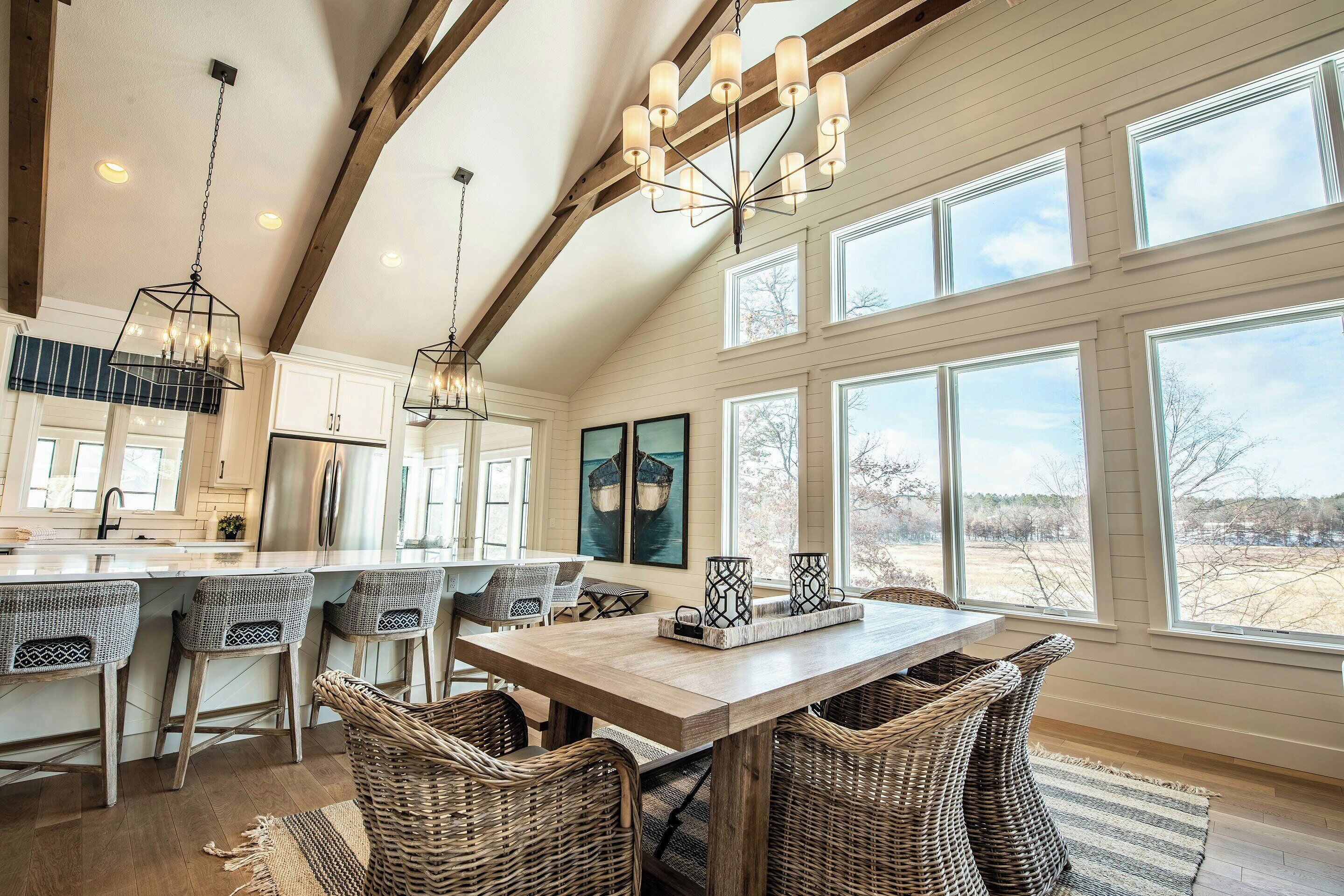A spacious kitchen with a large island, bar stools, and a dining table with wicker chairs.