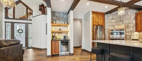 Una cocina moderna con pared de piedra, vigas de madera, una barra de café y horno empotrado.