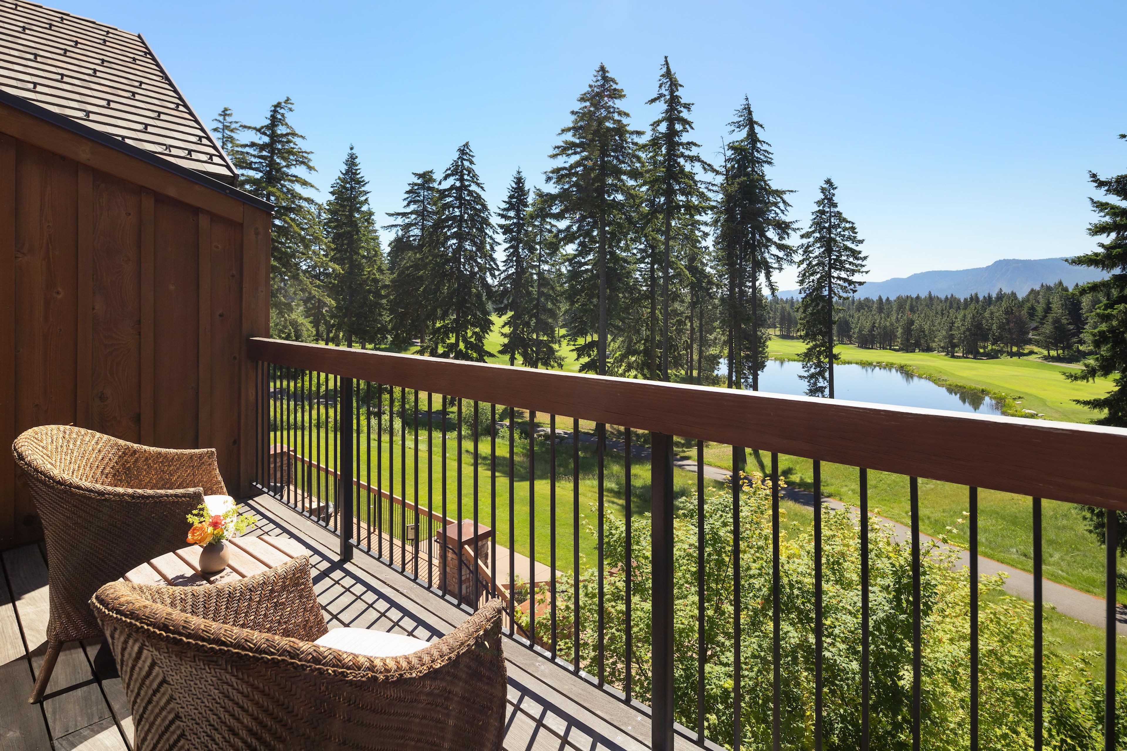 Una terraza de madera con muebles de mimbre que da a un lago y un bosque.