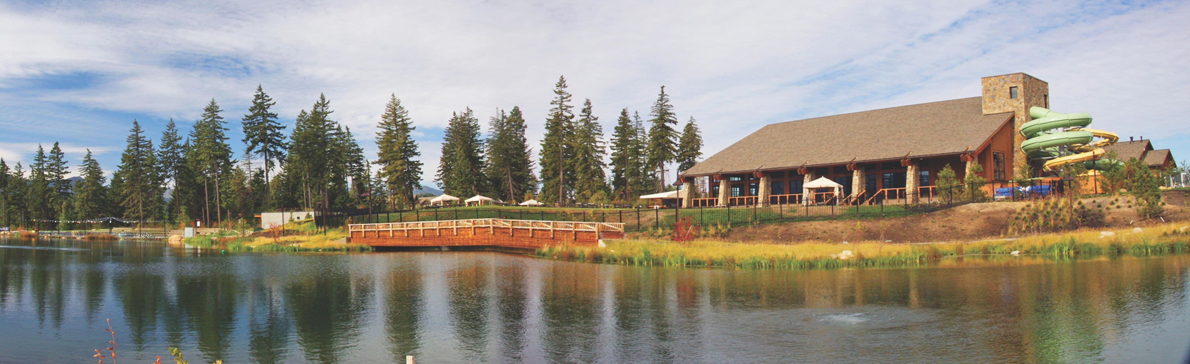 A lodge with a dock, surrounded by a forest and a lake.