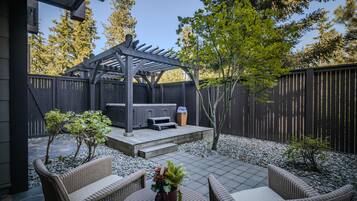 Une terrasse avec mobilier d’extérieur, une pergola et un espace barbecue.