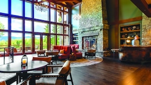 A spacious room with large windows, a stone fireplace, and a bar area. - Suncadia Resort, a Destination by Hyatt Residence (Cle Elum)