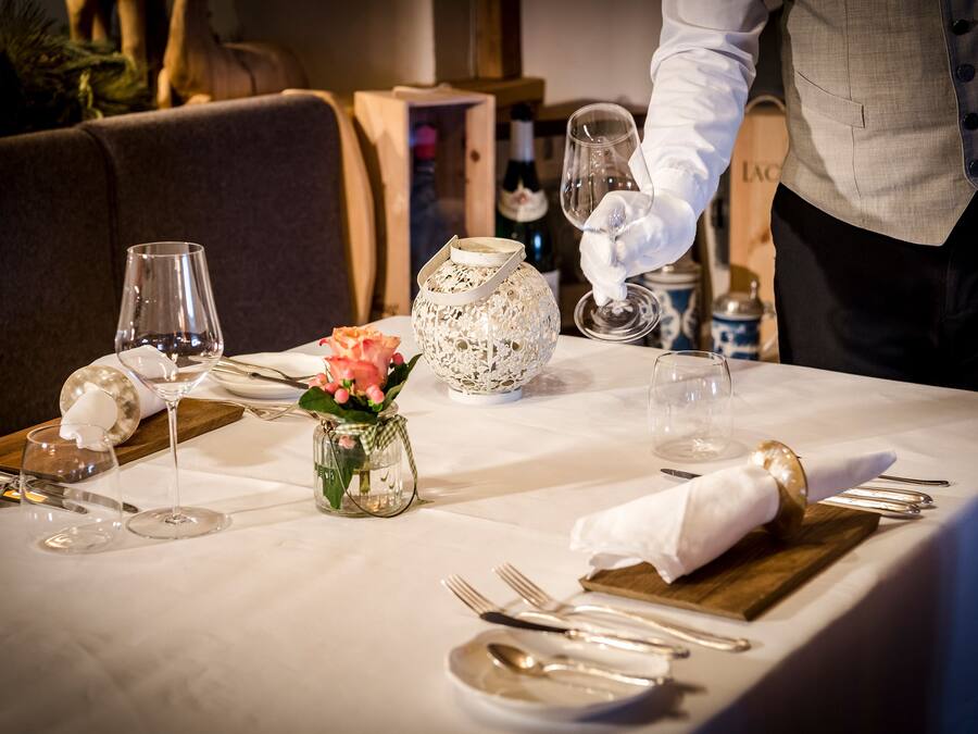 A table set for dining with a wine bottle, glasses, and a decorative vase.