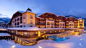 Un hotel grande de varios pisos con piscina, rodeado de montañas nevadas.