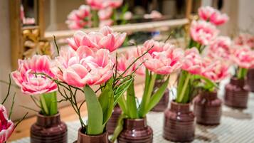 Flere små brune vaser med lyserøde blomster på et bord.