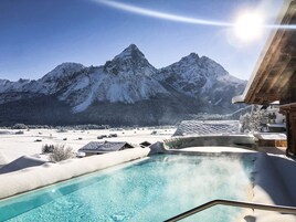 Una piscina techada, una piscina al aire libre, sombrillas