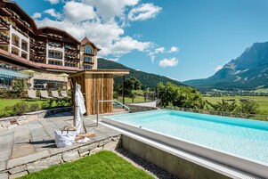 Una piscina techada, una piscina al aire libre, sombrillas
